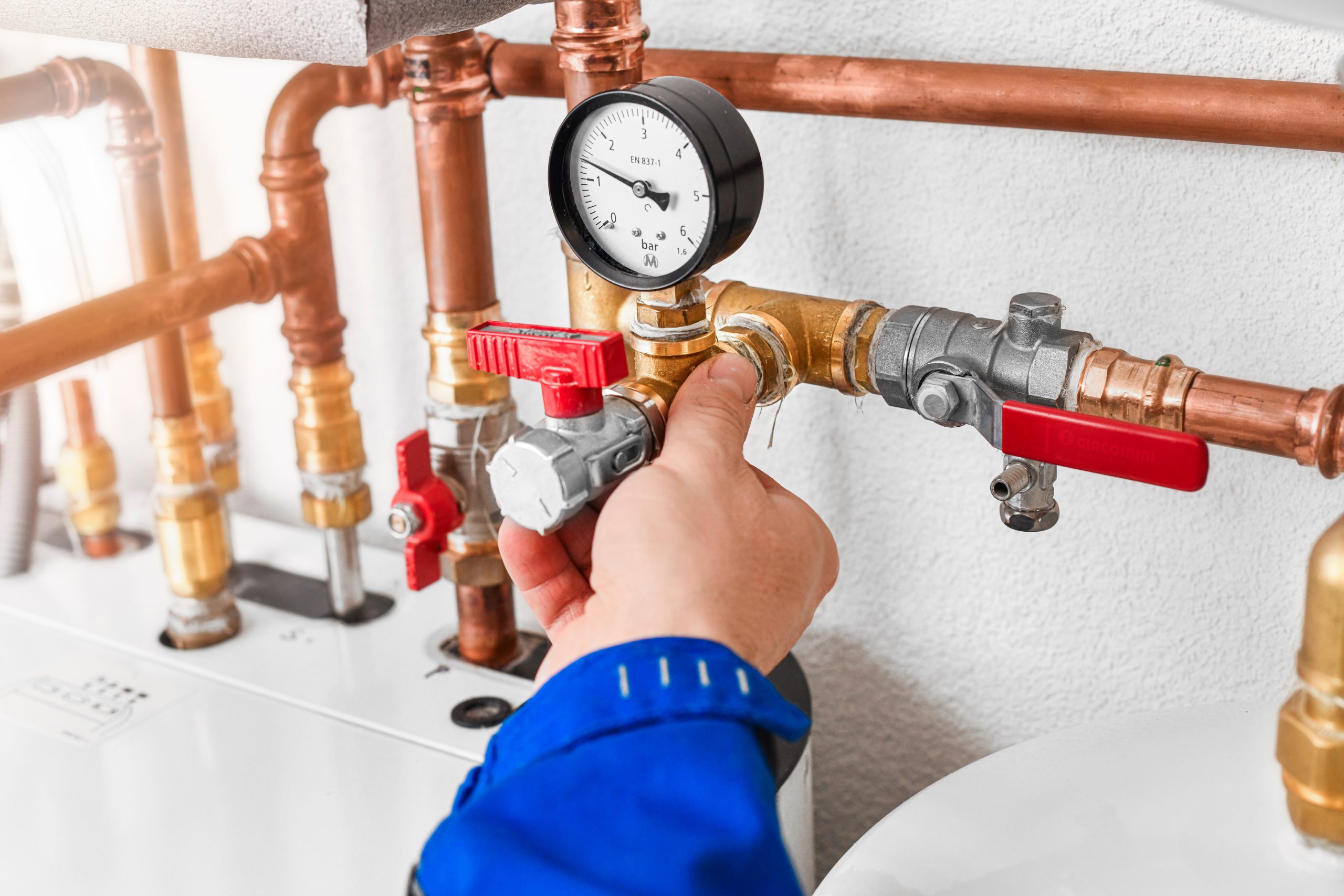 Technician adjusting water pressure valve to monitor well pump system performance.