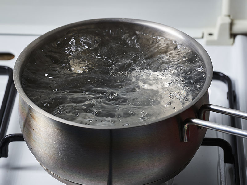 Water boils in a stainless steel pot.
